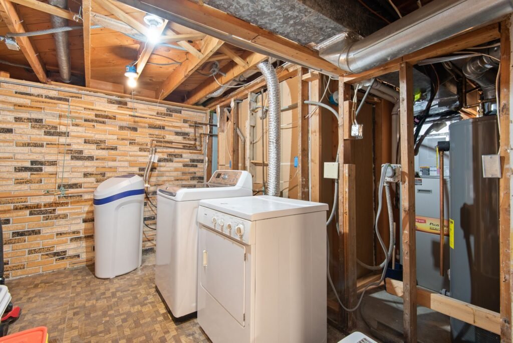 A dryer moved away from the wall so lint can be cleaned from the floor and vent area